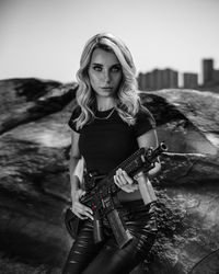 Portrait of young woman holding gun