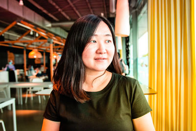 Smiling woman looking away while sitting at cafe