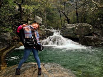 Full length portrait of woman standing against waterfall