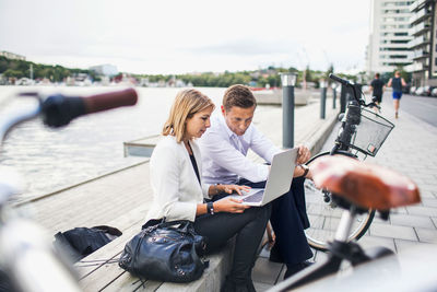 Business people working on laptop against clear sky