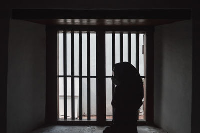 Side view of silhouette woman standing against window in building