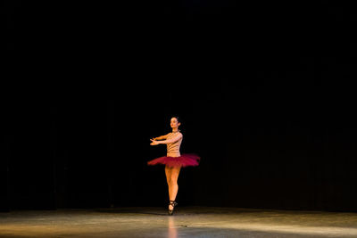 Full length of woman dancing against black background