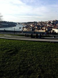 People by river against sky in city