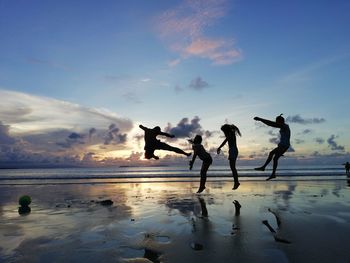 Silhouette people at beach against sky during sunset