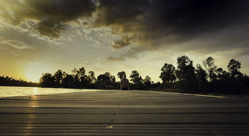 Man exercising on pier over lake during sunset