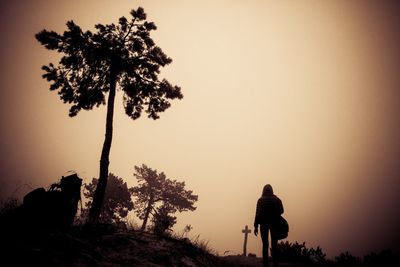 Rear view of woman walking against sky in foggy weather