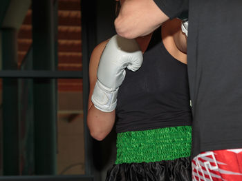 Midsection of coach with boxer practicing boxing in club