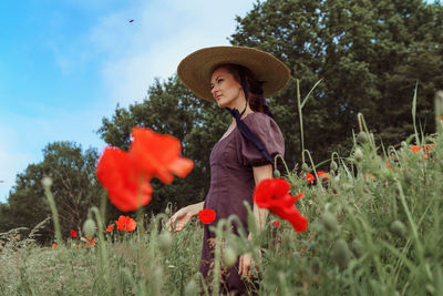 Young woman with red flowers on field