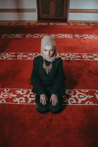 Woman in traditional clothing praying at mosque