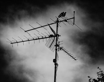 Low angle view of silhouette telephone pole against sky