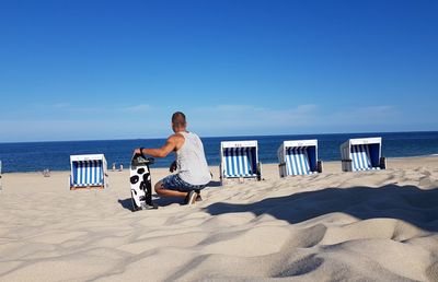 Full length of man on chair at beach against sky