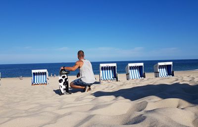 Rear view of man with skateboard at beach