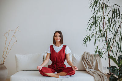 Young woman doing yoga at home. sitting in the lotus position