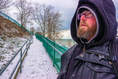 Hooded man standing on snowy walkway