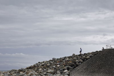 Man standing on rock against sky