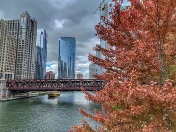 Bridge over river by buildings against sky