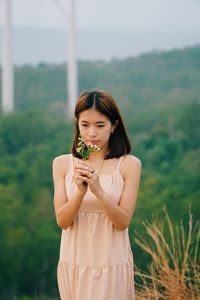 Young woman holding plant standing outdoors