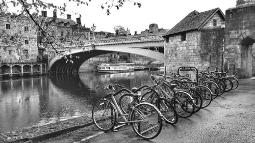 Bicycles on bridge over river against buildings in city