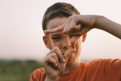 Portrait of a smiling little boy in a orange t-shirt and playing outdoors on the field at sunset