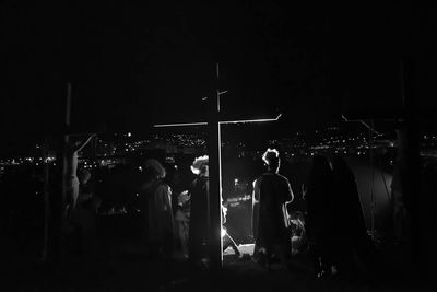 People standing by cross at night