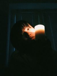 Close-up portrait of young woman with a candle in her hands