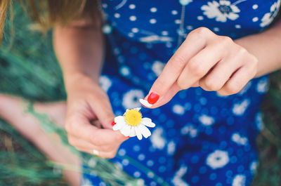 Midsection of woman plucking petal from flower