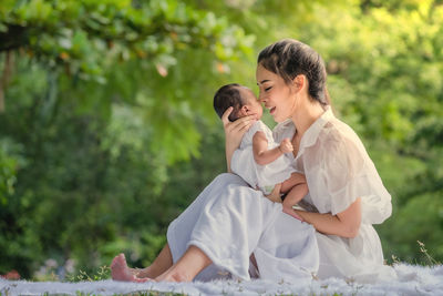 Woman carrying newborn daughter while sitting at park