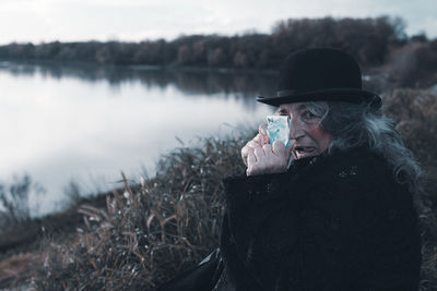 Side view of young woman standing against lake