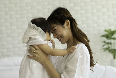 Smiling mother embracing daughter at home