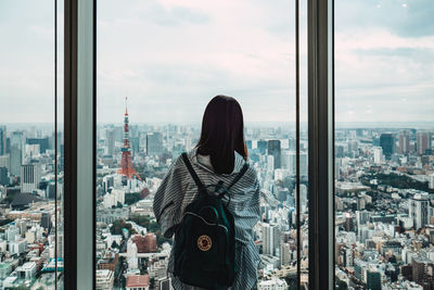 Rear view of woman looking at cityscape against sky