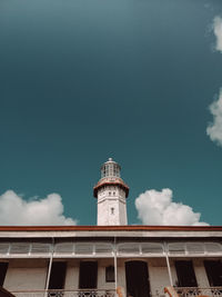 Low angle view of lighthouse by building against sky