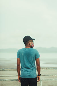 Side view of man standing at beach against sky