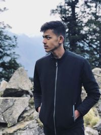 Young man standing against trees