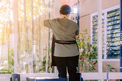 Rear view of man standing by window