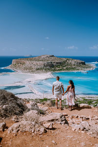 Rear view of couple at beach against sky