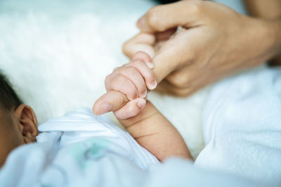 Close-up of baby holding mother finger