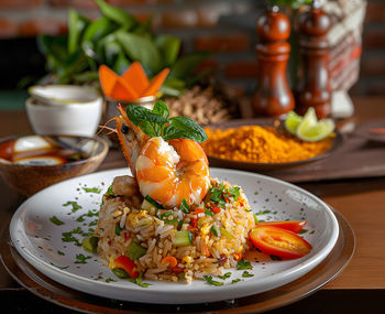 Shrimp fried rice with vegetables, green onions and lime in a black pottery bowl. traditional thai 