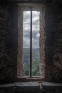 Stone wall by sea against sky seen through window