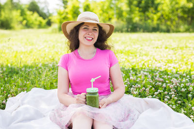 Portrait of a smiling young woman sitting on field