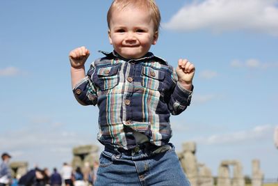 Portrait of happy boy standing against sky