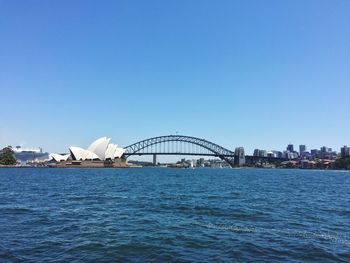 Bridge over cityscape against clear blue sky