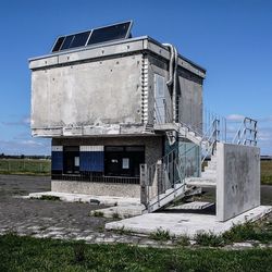 Built structure on grassy field against blue sky