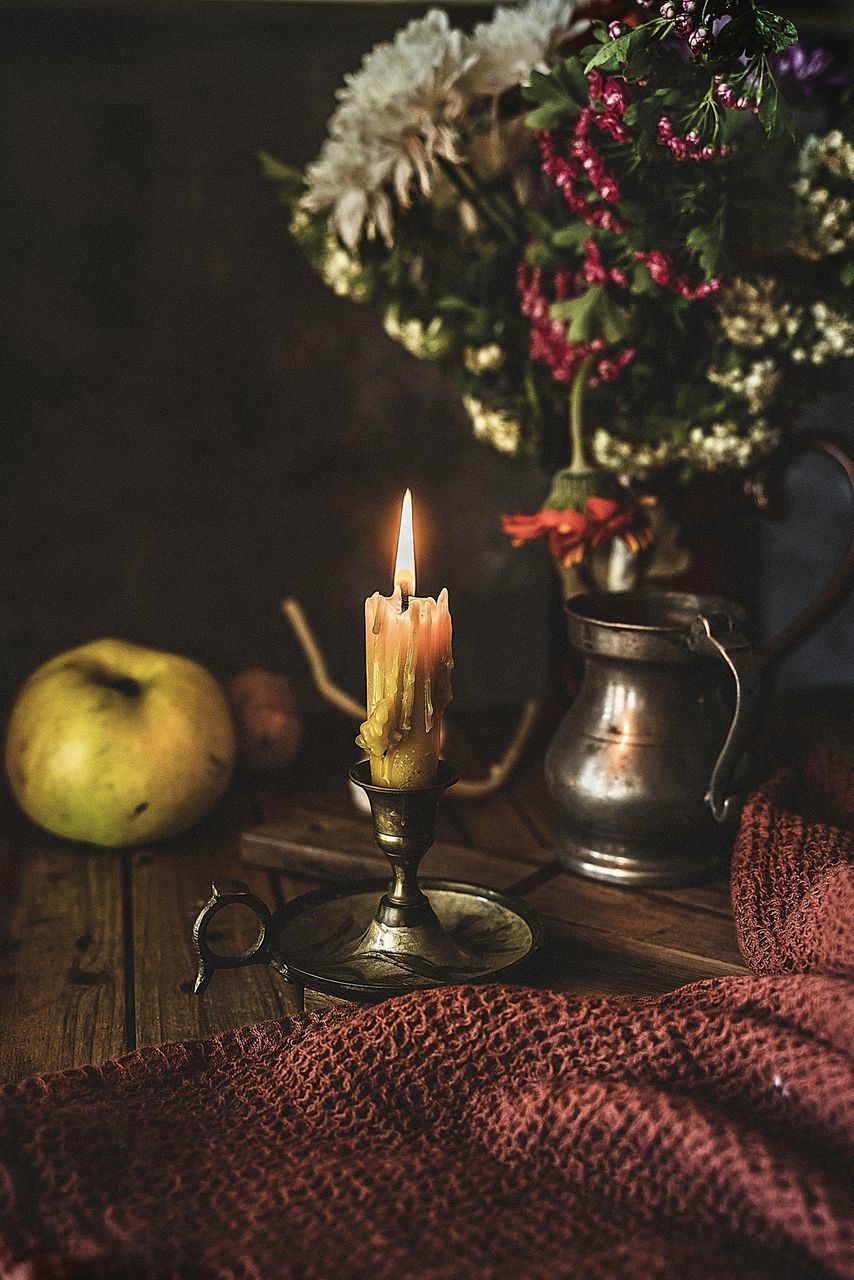 CLOSE-UP OF ILLUMINATED CANDLE ON TABLE