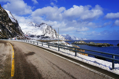 Road by snowcapped mountain against sky