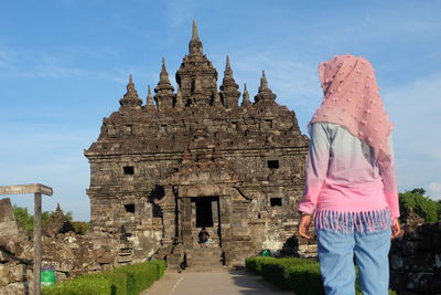 Woman standing by temple against sky