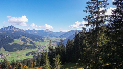 Scenic view of trees and mountains against blue sky