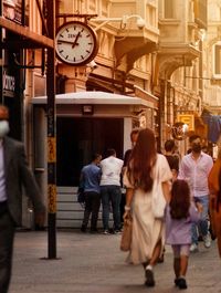 Rear view of people walking on street in city