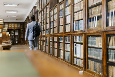 Businessman with backpack walking in library