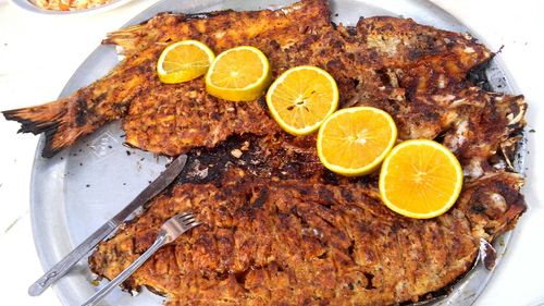 Close-up of fried fish with lemon slices in plate