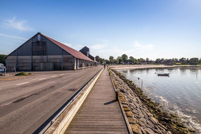 Footpath by river amidst buildings against sky